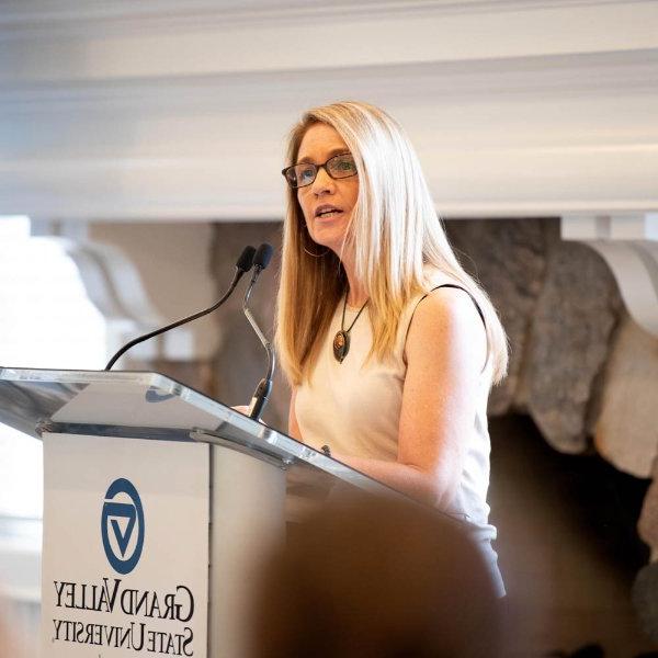 Lisa Perhamus, director of the Padnos/Sarosik Center for Civil Discourse, speaks from a podium in front of a fireplace in the Alumni House